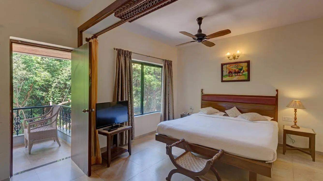 Spacious forest premium room with comfortable bed, sofa and private balcony overlooking lush forest at Ramsukh Resort Mahabaleshwar